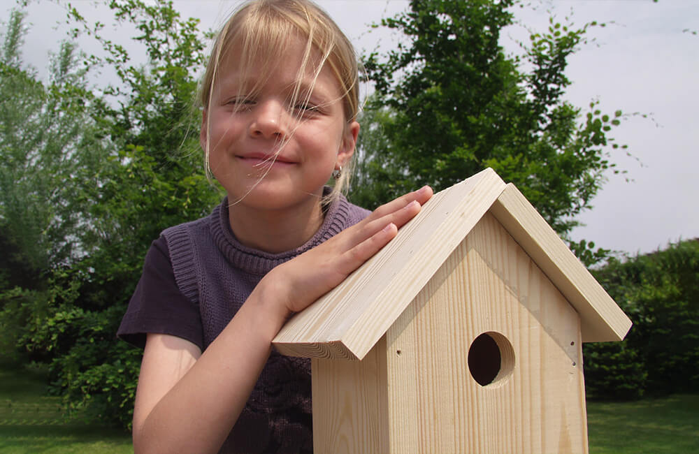 Child smiles while presenting the assembled nest box building kit