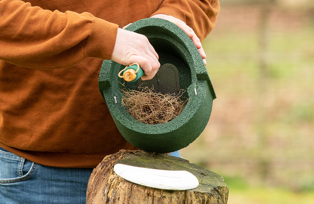 The cover of a woodstone nest box has been removed and is being cleaned from the inside.